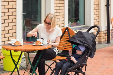 Bir yaşındaki çocuğunu sokak bir kafede ile Genç Anne