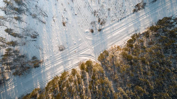 Повітряний вид на дорогу, що проходить через засніжений зимовий ліс. Вид зверху — стокове фото