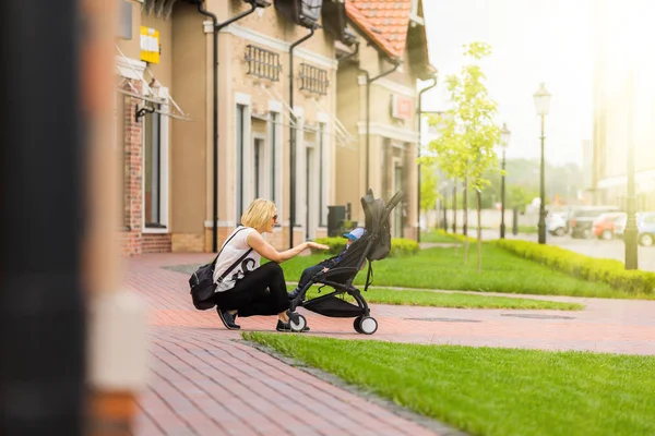 Madre porta il suo bambino in un passeggino per una passeggiata . — Foto Stock