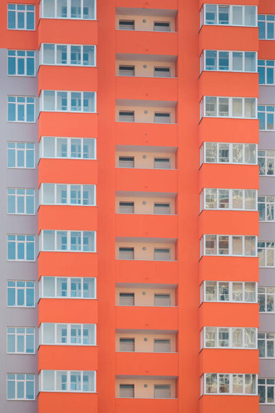 Fragment of the facade of a brand new high-rise residential building in a bright orange color