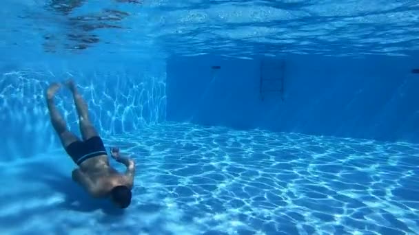 Hombre nadando en una piscina con agua azul — Vídeo de stock