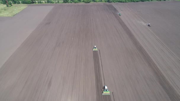 Vliegen op een copter over een grijze veld met 4 werkende tractoren. Luchtfoto — Stockvideo
