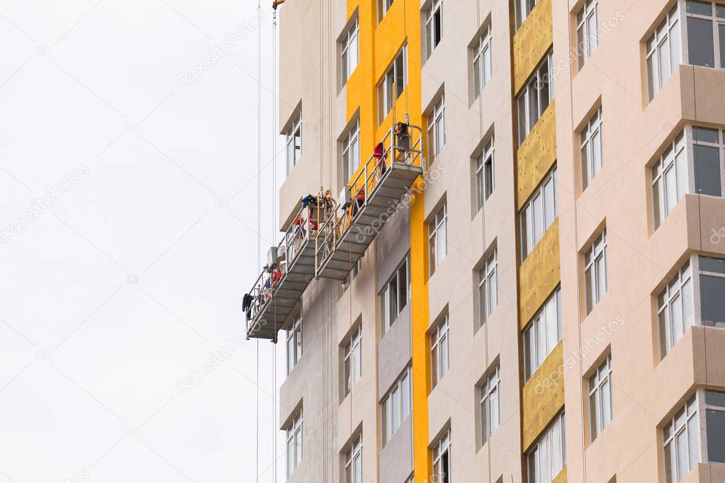 Builders paint the facade of a high-rise residential building