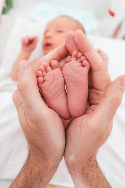 Füße eines neugeborenen Jungen in die Arme seines Vaters gewickelt — Stockfoto