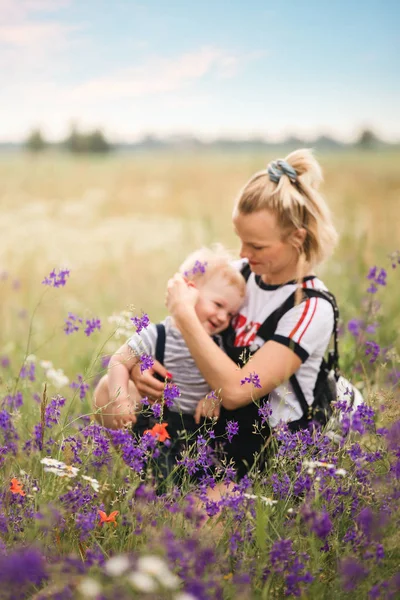 Mère et enfant jouant dans le champ avec des fleurs . — Photo