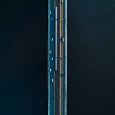 İki şeritli köprü ve karanlık su bir arka plan üzerinde metro veya tren rayları. Havadan görünüm