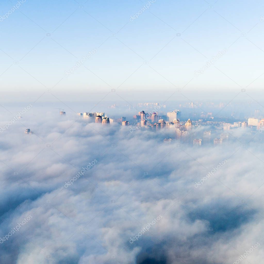 The city is covered with thick fog and protruding from it where neither where high-rise buildings