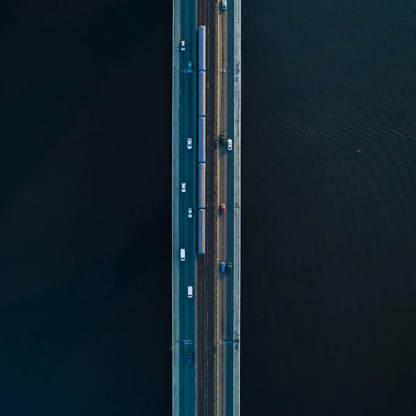 Puente con dos carriles y rieles de metro o tren sobre un fondo de agua oscura. Vista aérea —  Fotos de Stock