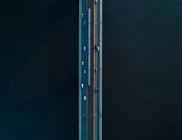 Puente con dos carriles y rieles de metro o tren sobre un fondo de agua oscura. Vista aérea — Foto de Stock