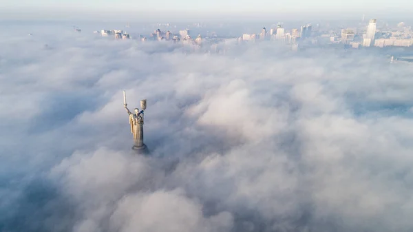 Nuvens espessas de nevoeiro de outono e o monumento da Pátria saindo deles — Fotografia de Stock