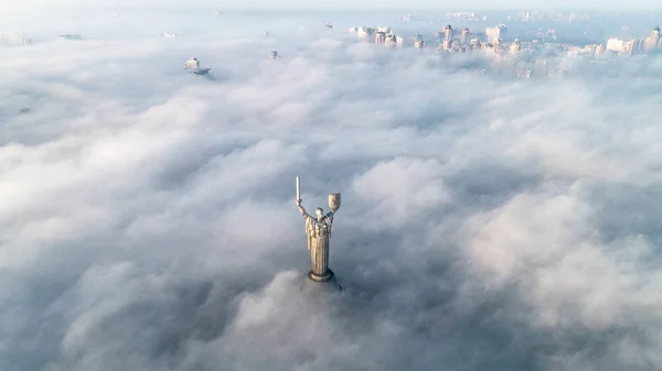 Nubi spesse di nebbia autunnale e il monumento della Patria che ne fuoriesce — Foto Stock