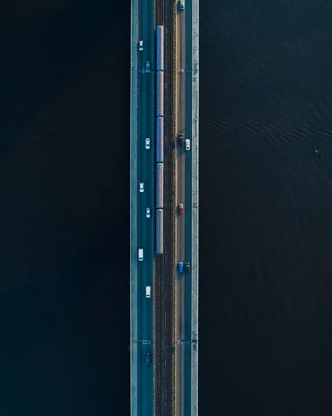 Brücke mit zwei Fahrspuren und U- oder S-Bahnschienen vor dunklem Wasser. Luftbild — Stockfoto