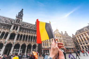 Kadın turist elinde Brüksel Grand-Place Meydanı arka planda Belçika bayrağı tutar, Belçika