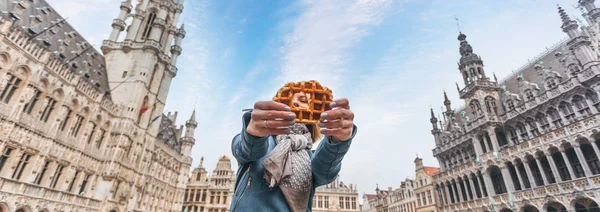 Jovem mulher bonita segurando um waffle belga tradicional no fundo da Grande Praça do Mercado em Bruxelas, Bélgica — Fotografia de Stock