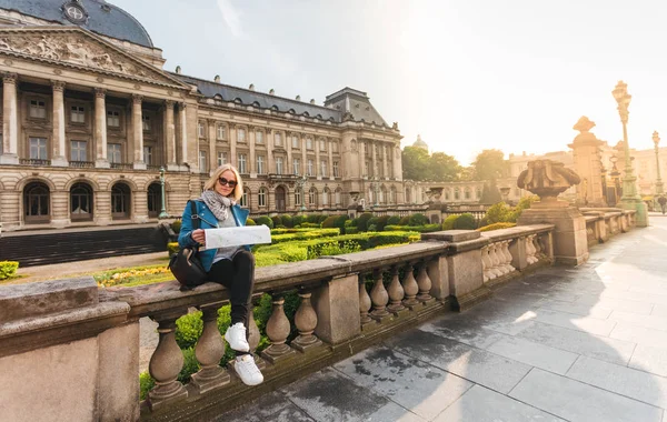 Viajero femenino se sienta en el parapeto en el fondo del Palacio Real de Bruselas y mira en el mapa, Bélgica — Foto de Stock