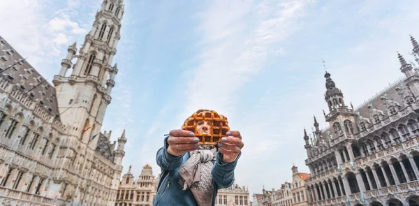 年轻的漂亮女人拿着传统的比利时华夫饼在比利时布鲁塞尔大市场广场的背景 — 图库照片