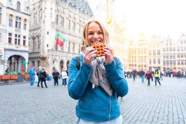 Молода красива жінка тримає традиційні бельгійські вафельних на тлі великої ринкової площі в Брюсселі, Бельгія — стокове фото