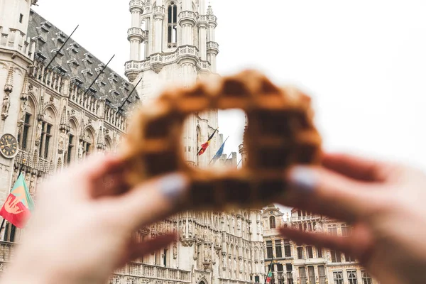 Vista da Câmara Municipal de Bruxelas na Grand Place, em Bruxelas, através de um buraco no tradicional waffle belga . — Fotografia de Stock