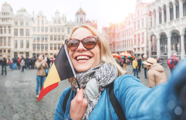 Mujer de puestos turísticos con la bandera de Bélgica en el fondo de la Grand-Place o la Plaza del Gran Mercado en Bruselas — Foto de Stock