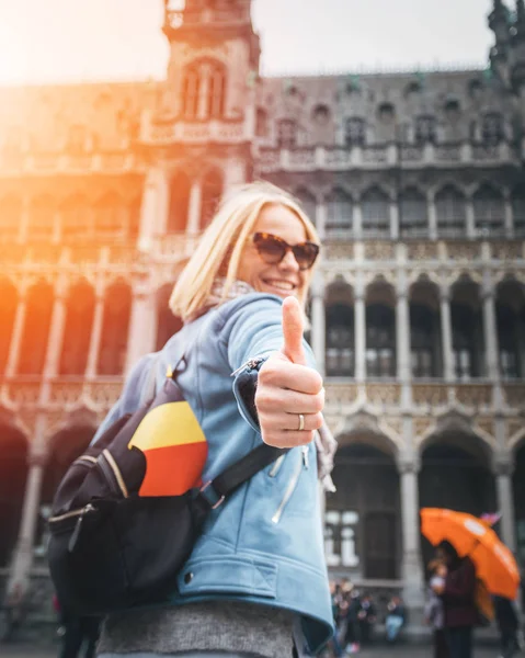 브뤼셀의 그랜드 플레이스 스퀘어에 여성 여행자가 서서 엄지손가락을 치켜들고 벨기에. — 스톡 사진