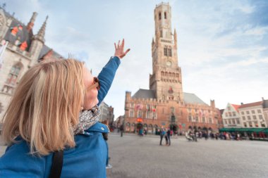 Genç kadın Bruges Belfort Kulesi'nde el gösterir, Belçika
