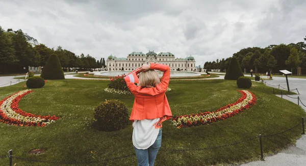Mujer caucásica adulta sosteniendo bandera austriaca en el fondo del palacio Belvedere —  Fotos de Stock