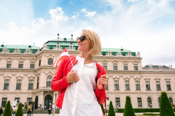 Viajero femenino con la bandera de Austria con el telón de fondo del Palacio del Belvedere Superior en Viena . — Foto de Stock