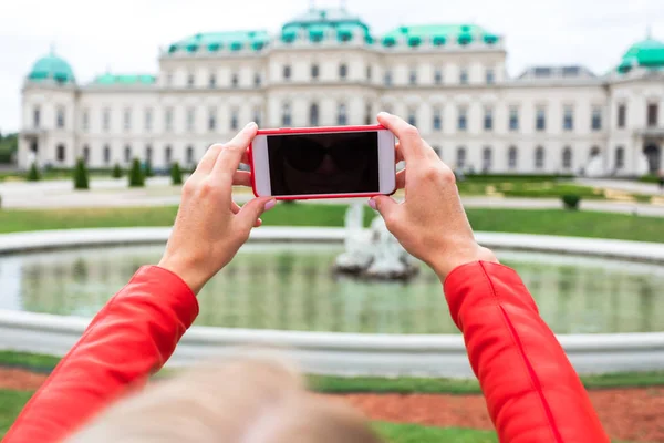 在维也纳上贝尔维迪尔宫的背景中，带着奥地利国旗的女旅行者. — 图库照片