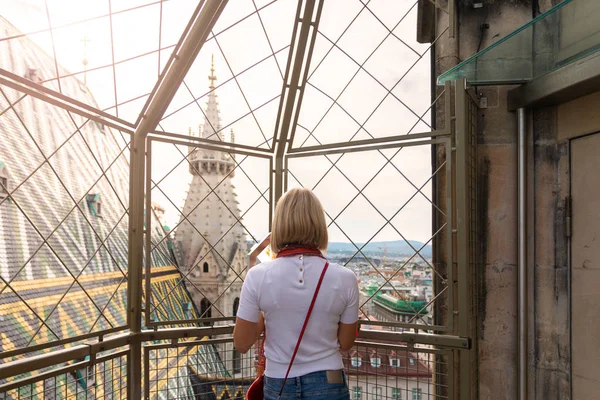 Uma mulher admira o panorama de Viena do ponto de vista da Catedral de Santo Estêvão e segura a bandeira da Áustria em suas mãos . — Fotografia de Stock