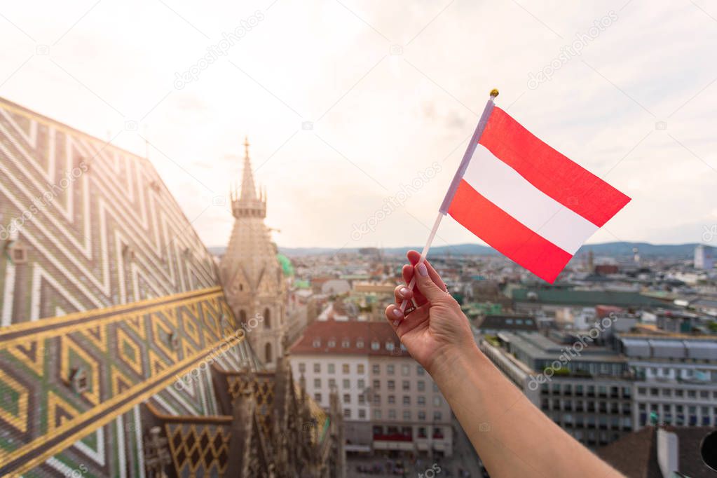 Woman holds Austria flag in hand against Vienna city panorama background.