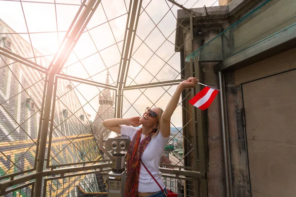 한 여성이 성 스티븐스 대성당의 관점에서 비엔나의 파노라마를 감상하고 손에 오스트리아의 국기를 들고 있다.. — 스톡 사진