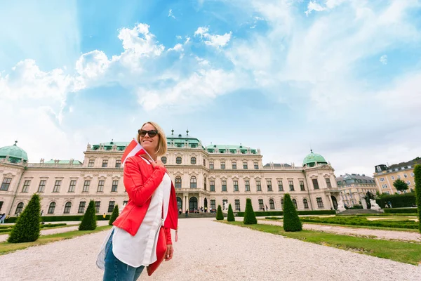 Viajero femenino con la bandera de Austria con el telón de fondo del Palacio del Belvedere Superior en Viena . — Foto de Stock