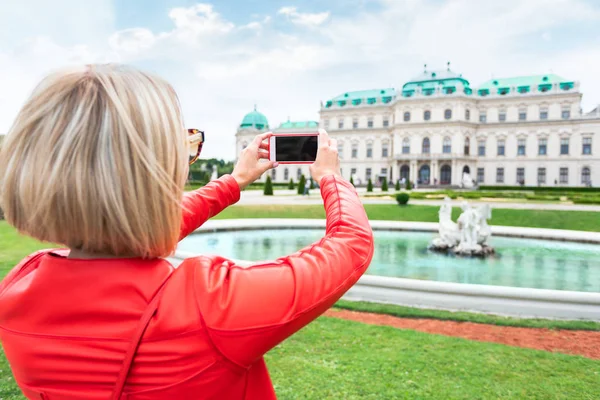 Viajero femenino con la bandera de Austria con el telón de fondo del Palacio del Belvedere Superior en Viena . — Foto de Stock