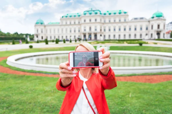 Viajero femenino con la bandera de Austria con el telón de fondo del Palacio del Belvedere Superior en Viena . — Foto de Stock