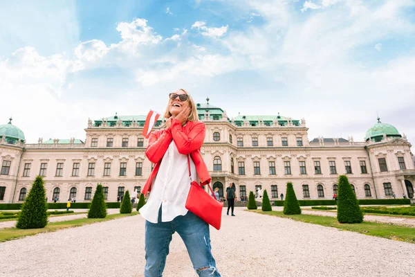 비엔나 의 어퍼 벨베데레 궁전을 배경으로 오스트리아의 국기를 가진 여성 여행자. — 스톡 사진