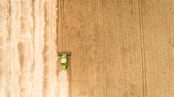 Maaimachine werkt in veld en maait tarwe. Oekraïne. Luchtfoto. — Stockfoto