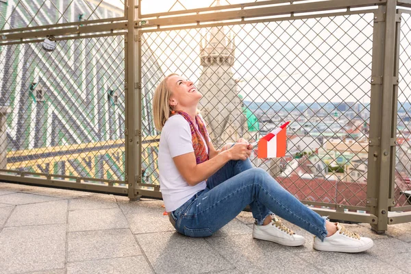 Una giovane ragazza si siede sul pavimento sullo sfondo del panorama di Vienna e sul tetto della Cattedrale di Santo Stefano a Vienna . — Foto Stock