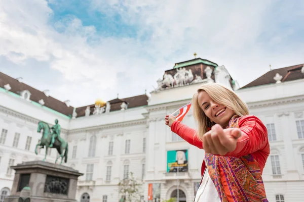 Uma jovem ergue-se com a bandeira da Áustria contra o pano de fundo da Biblioteca Nacional Austríaca em Viena . — Fotografia de Stock