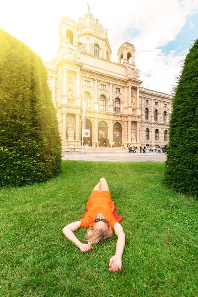 一位小女孩躺在草地上，躺在奥地利维也纳自然历史博物馆的背景下 — 图库照片