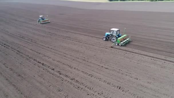 Circular flight Aerial view of two tractors driving one after another across the field — Stock Video