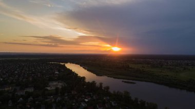 Yeşil çayır ve gün batımında bir nehir ile doğanın panoramik hava manzarası.