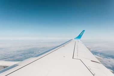 Mavi gökyüzüne karşı uçarken bir uçağın kanadı