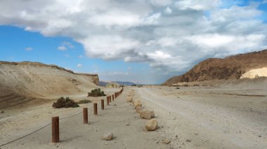 Ağır bulutlar ve beyaz kumlu yol