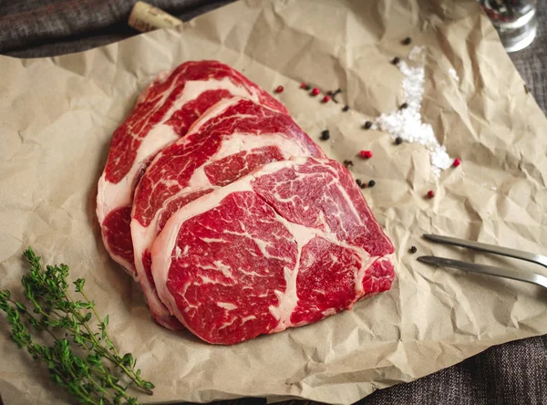 로즈마리 올리브 위에서 클로즈업 종이에 쇠고기 신선한 스테이크 — 스톡 사진
