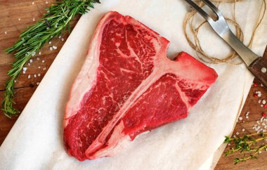 Bir ahşap tahta üzerinde otlar ile ham porterhouse biftek