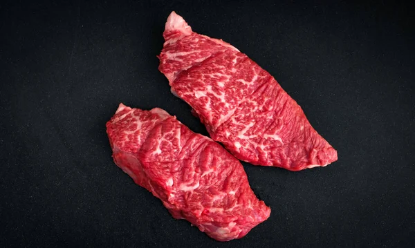 Dois bifes de carne crua marmorizada em um fundo preto no açougue — Fotografia de Stock