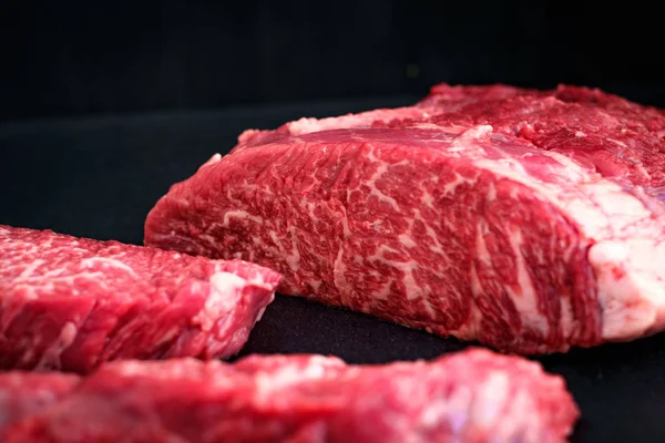 Fresh piece of raw marbled beef on a black background at the butcher — Stock Photo, Image