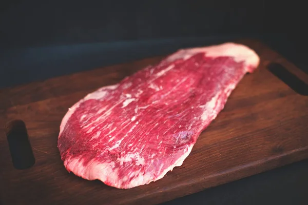 Uncooked flank steak of beef on a wooden Board
