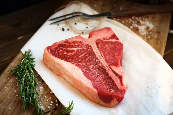 Bife cru com ervas em uma tábua de madeira — Fotografia de Stock