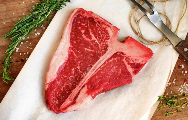 Rohes Porterhouse-Steak mit Kräutern auf Holzbrett — Stockfoto